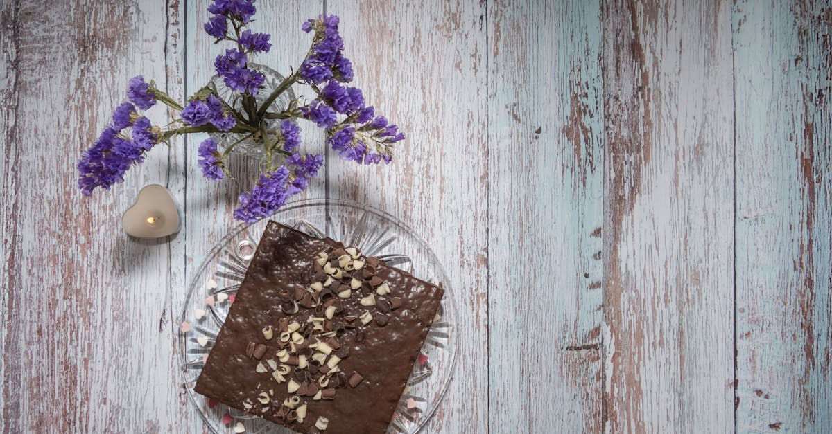 chocolate brownie on rustic table with delicate purple flowers and a candle perfect dessert setting