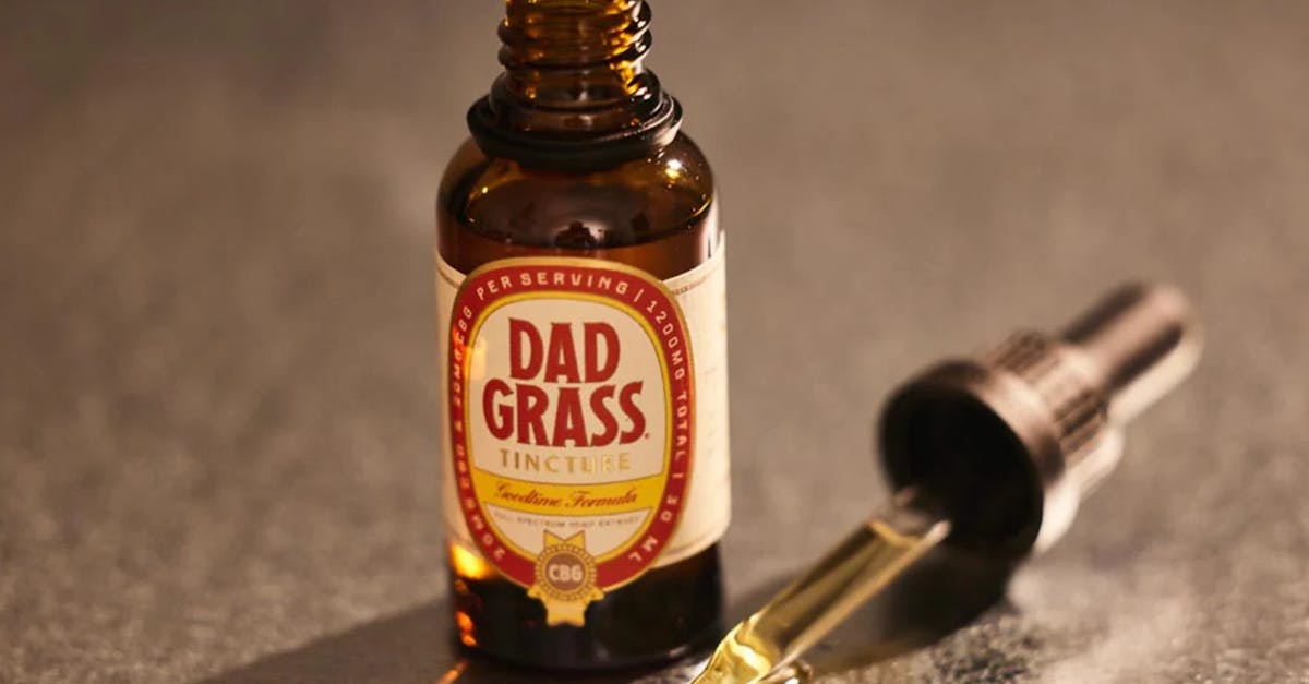 close up image of a dad grass tincture bottle and dropper against a neutral background