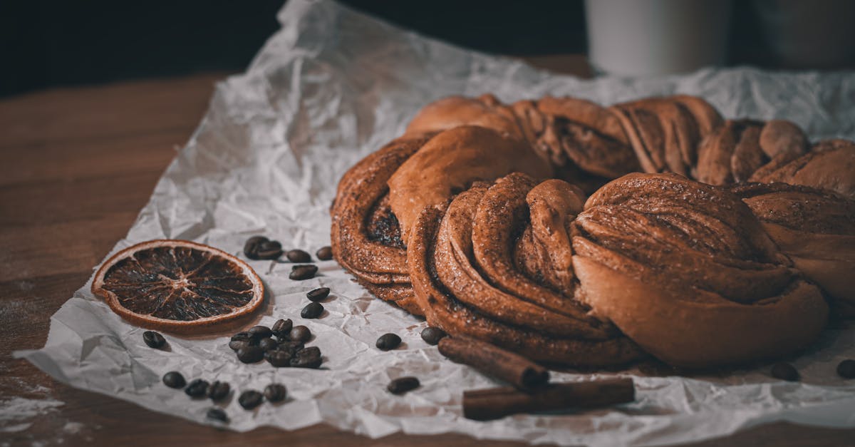 close up of a delicious cinnamon pastry on paper accompanied by coffee beans and a dried orange sli 2