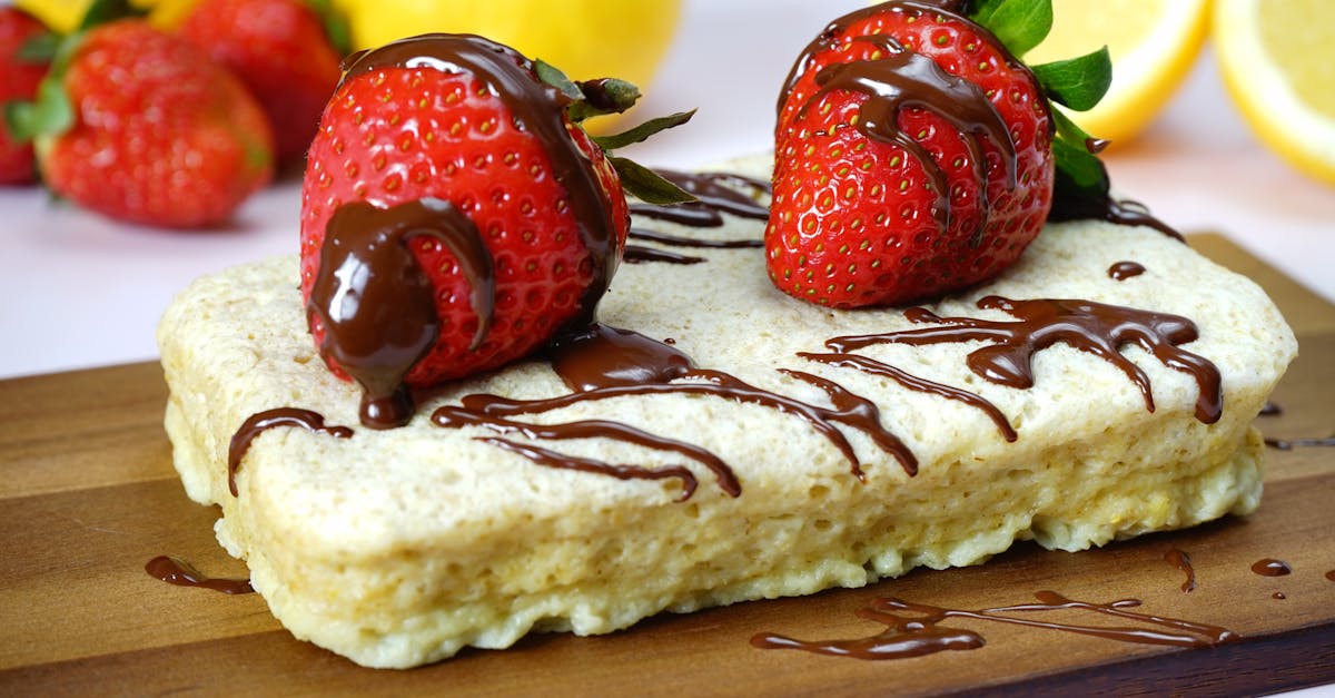 close up of a dessert topped with strawberries and chocolate drizzle on a wooden board