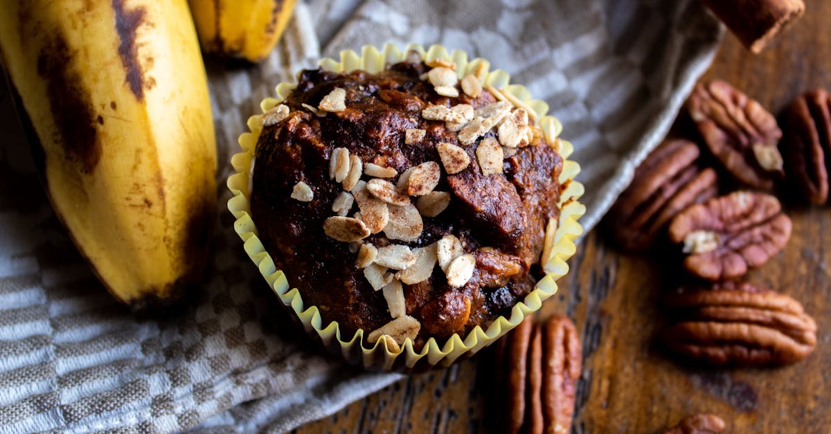 close up of a flavorful banana nut muffin topped with oats surrounded by fresh ingredients