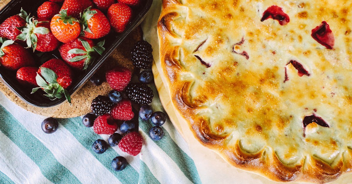 close up of a golden brown pie surrounded by fresh strawberries raspberries blueberries and black 1