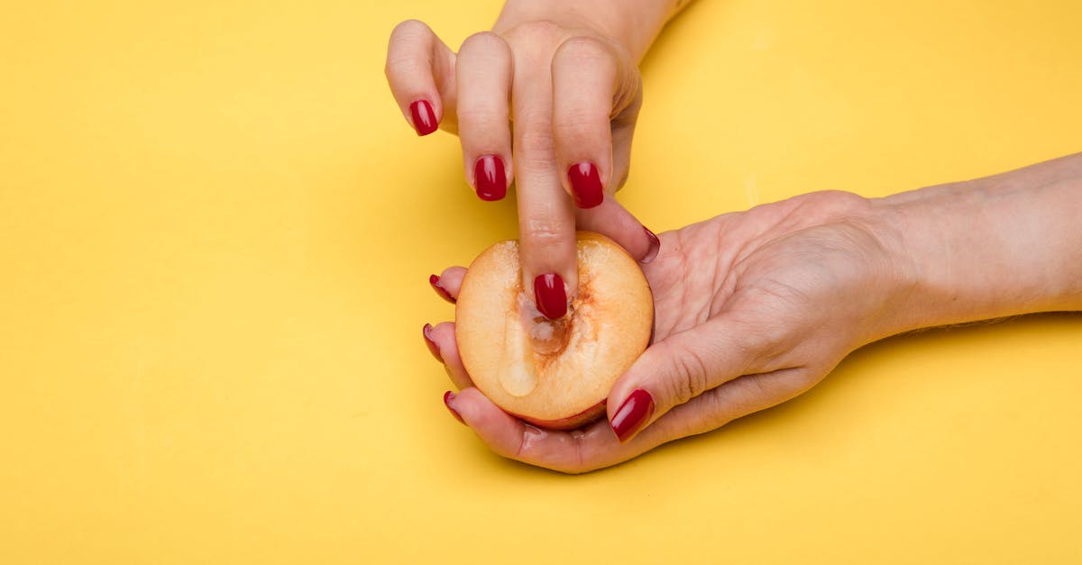 close up of a hand holding a peach with a yellow background symbolizing conceptual artistry