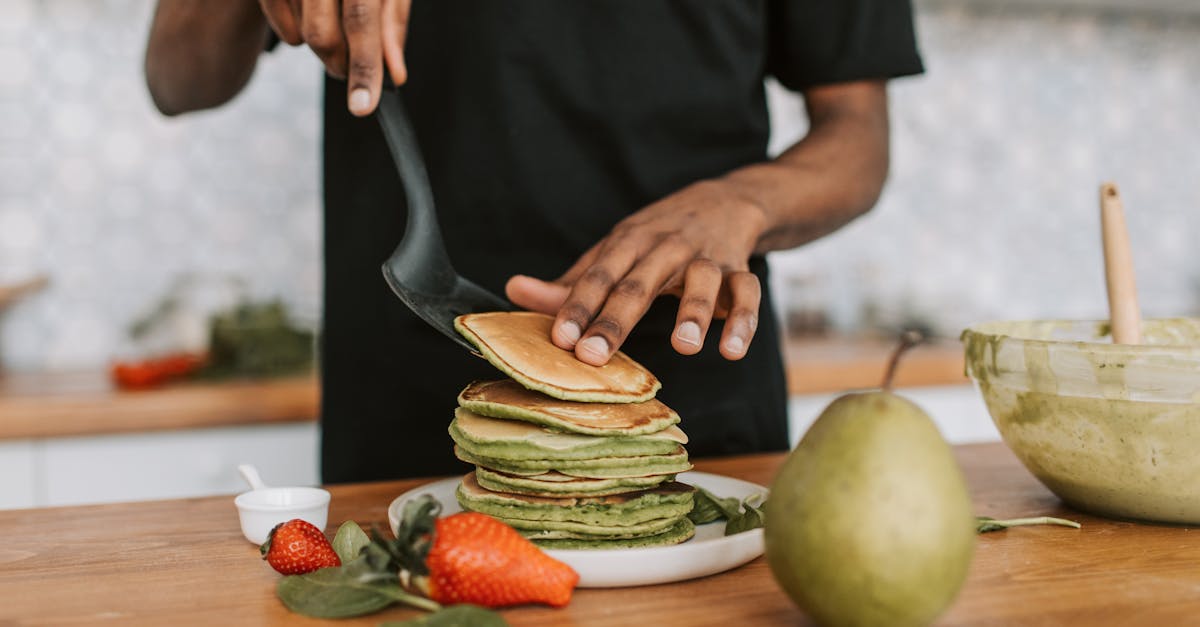 close up of a person preparing green pancakes with fresh fruit in a kitchen setting 2