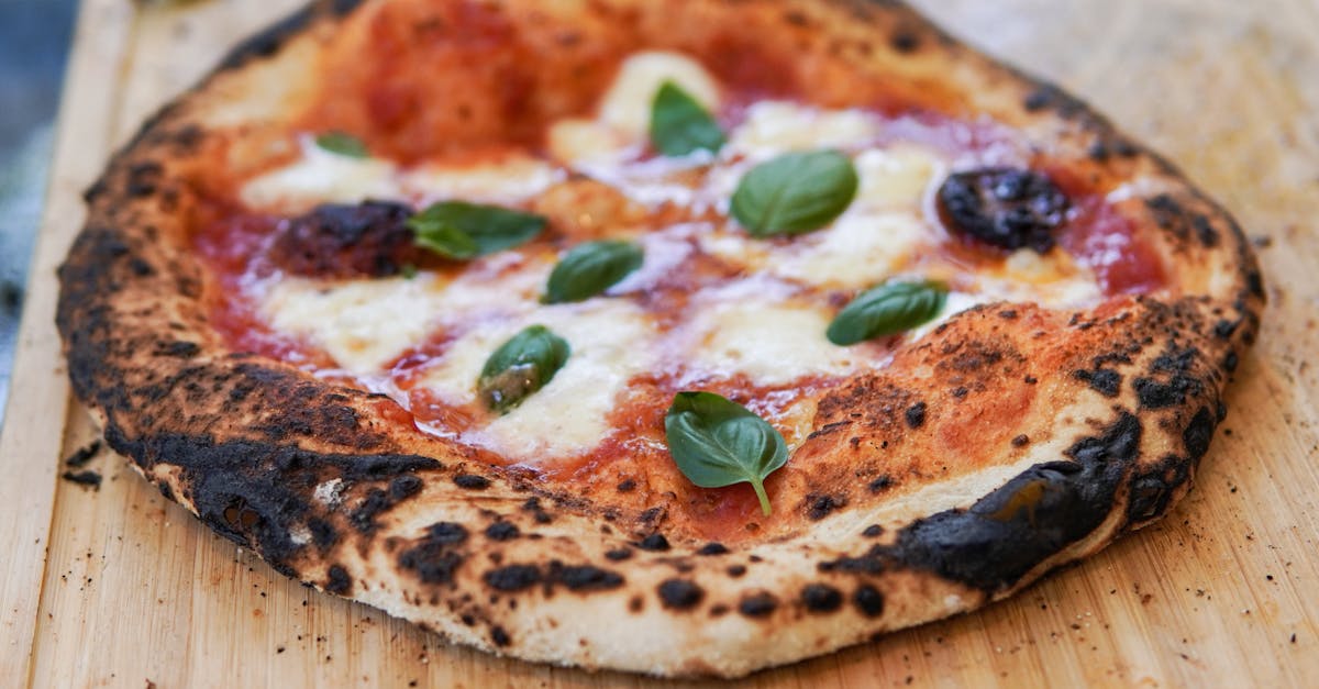 close up of a wood fired margherita pizza with fresh basil on a wooden surface