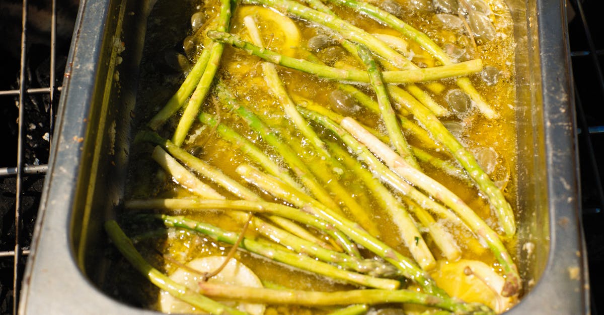 close up of asparagus cooking in a buttery garlic and lemon sauce on a grill 1