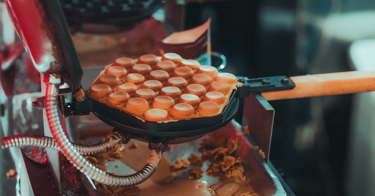 close up of bubble waffles in a waffle iron showcasing the baking process