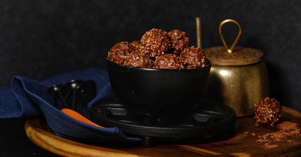 close up of chocolate hazelnut truffles in a black bowl with rustic kitchenware background 12
