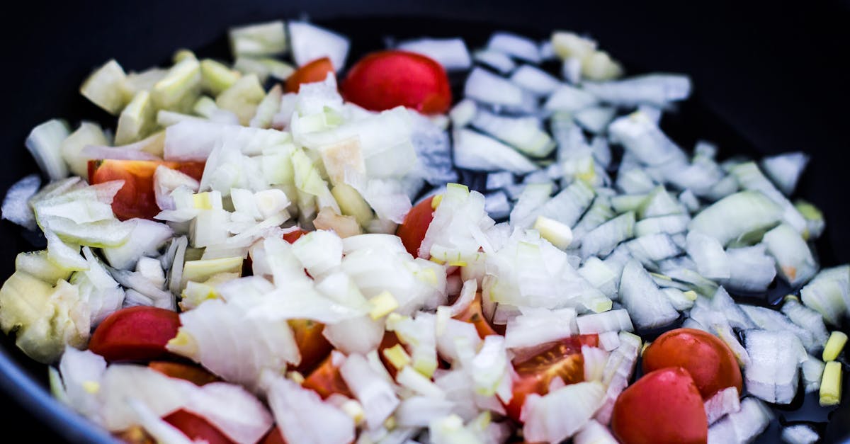 close up of chopped onions and cherry tomatoes in a pan perfect for culinary themes