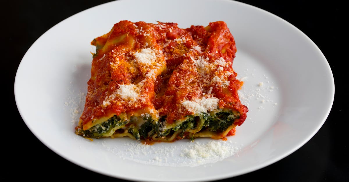 close up of classic spinach and ricotta lasagna topped with tomato sauce and parmesan on a white pla 1