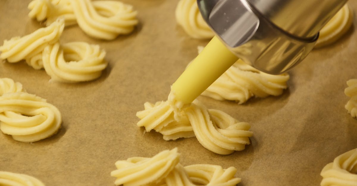 close up of cookie dough being piped into swirls on parchment paper using a pastry bag