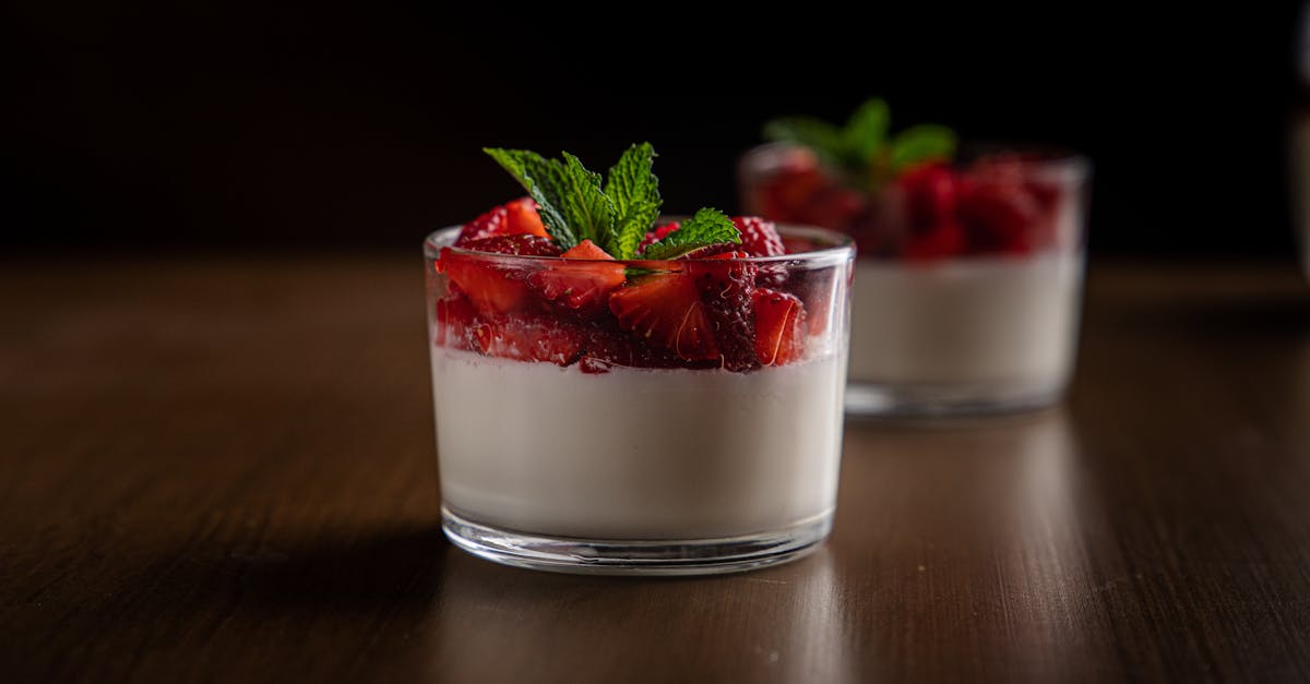 close up of creamy panna cotta topped with fresh strawberries and mint served in a glass