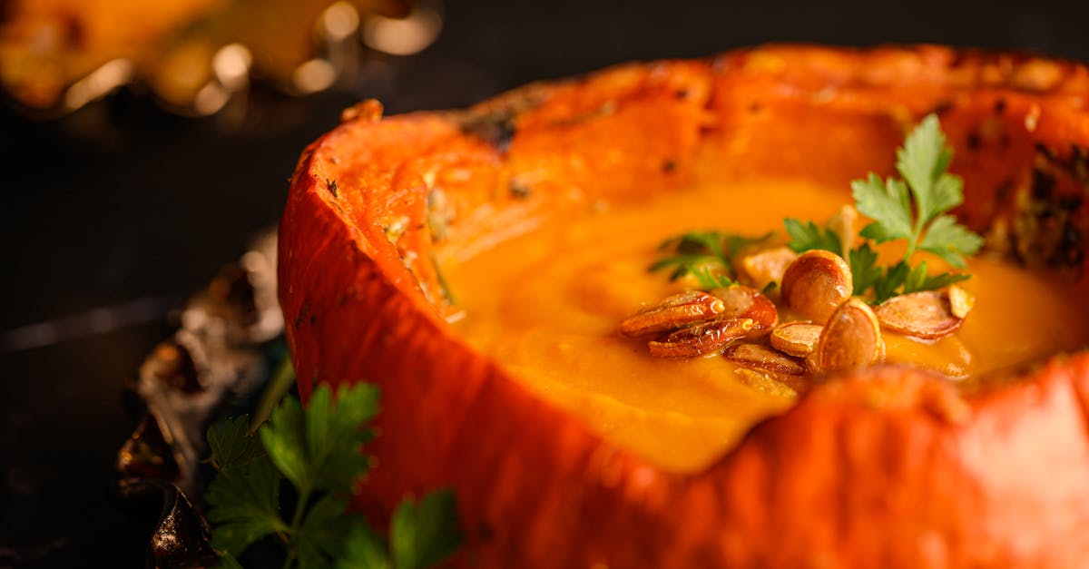 Home close up of creamy pumpkin soup garnished with seeds and parsley in a pumpkin bowl