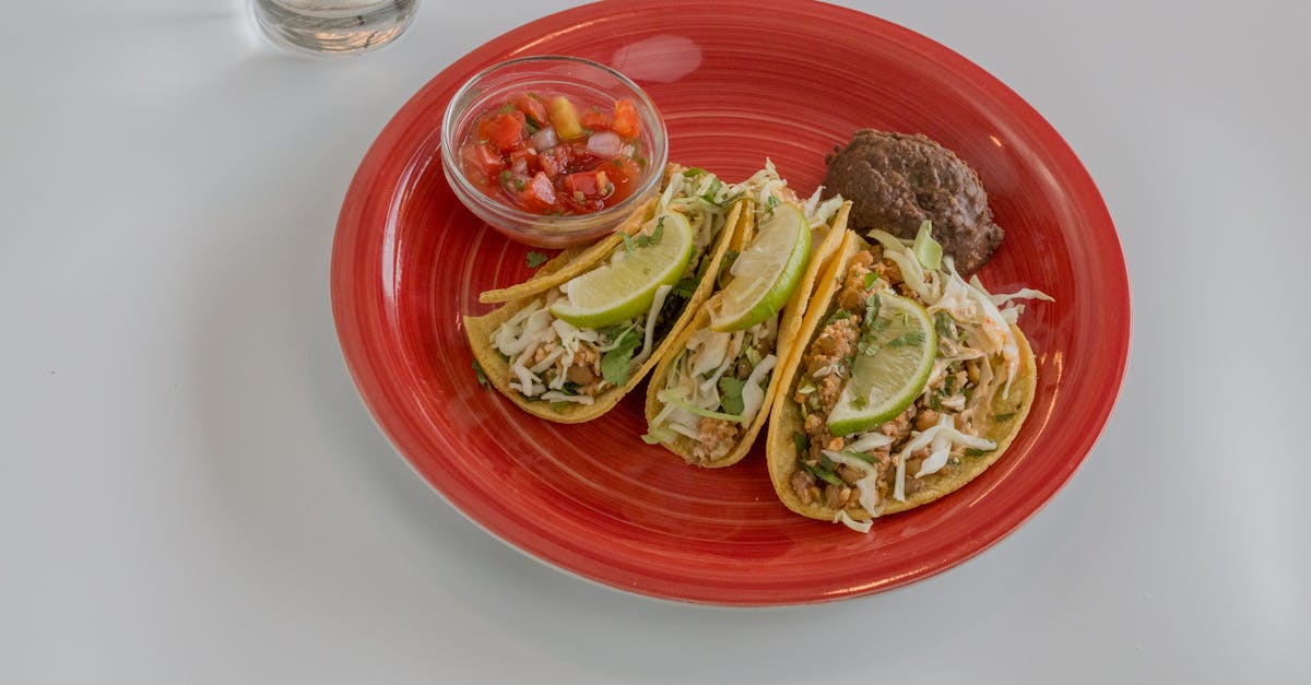 close up of delicious mexican tacos with lime salsa and beans on a vibrant red plate