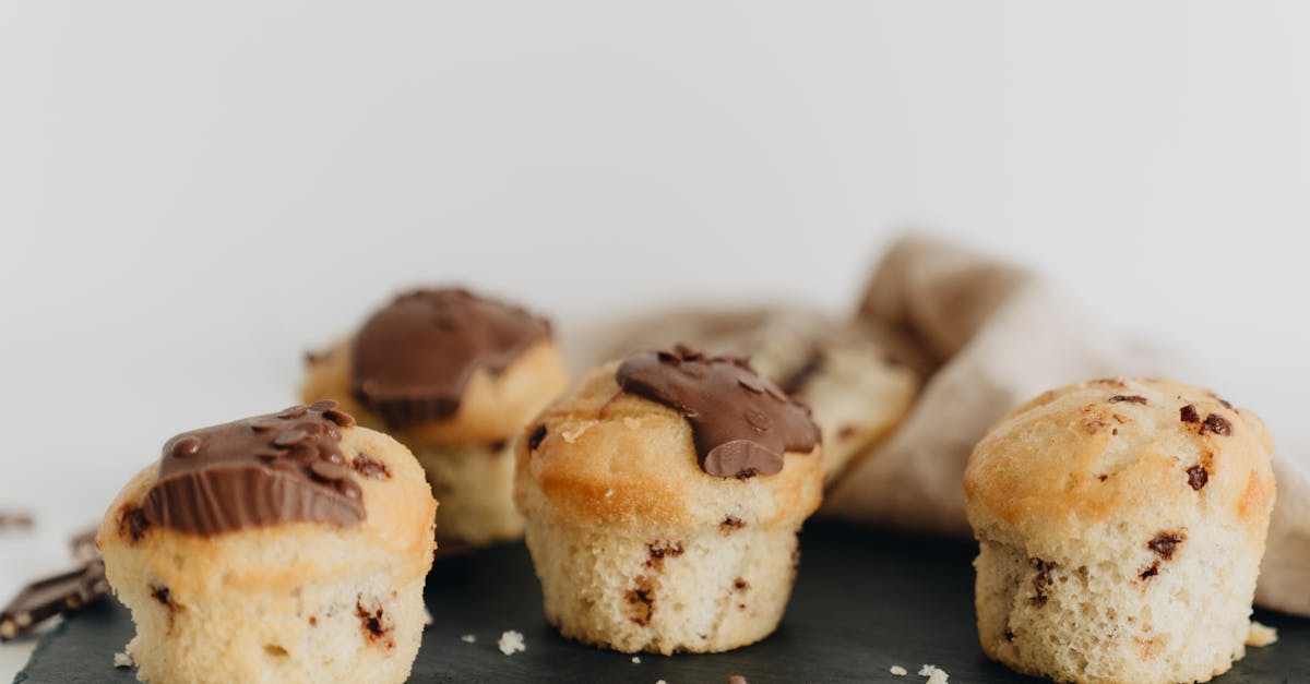 close up of four chocolate chip muffins with melted chocolate topping on a slate plate perfect for 1