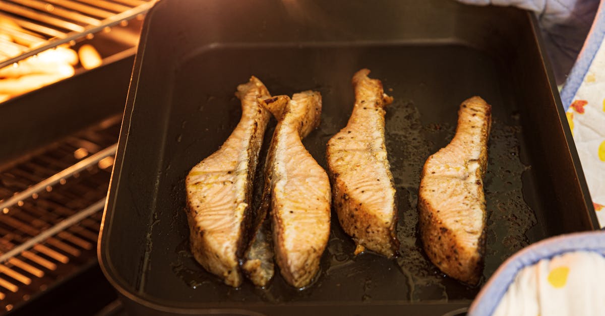 close up of four seasoned salmon fillets being baked in an oven with mitts
