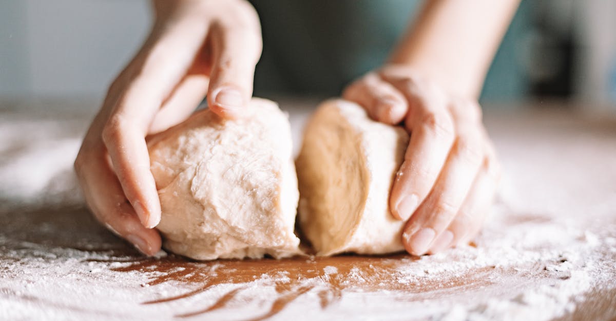 close up of hands kneading dough on a floured surface showcasing food preparation indoors