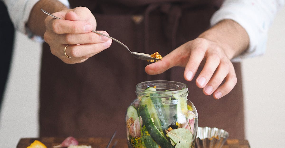 close up of hands preparing homemade pickles with fresh vegetables in a glass jar on a wooden board 3