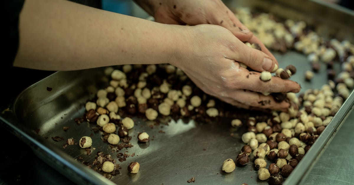 close up of hands sorting fresh hazelnuts on a metal tray in a kitchen setting