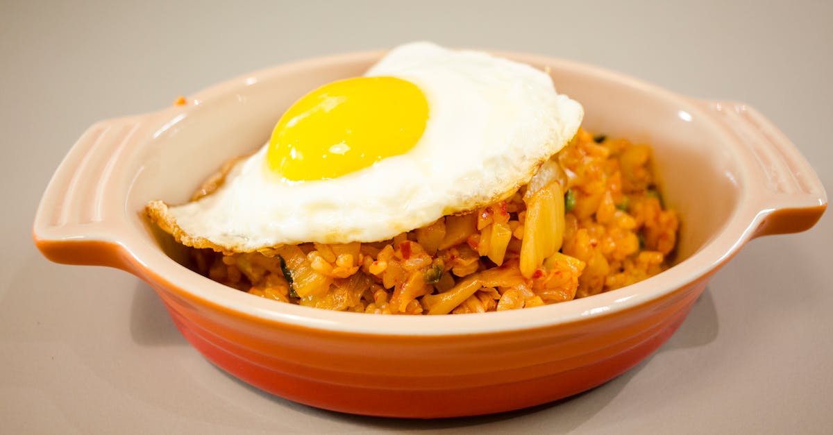 close up of kimchi fried rice topped with a sunny side up egg in a ceramic dish