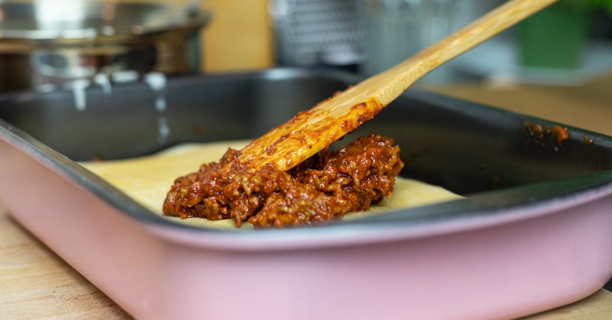 close up of layering meat sauce on lasagna in a pan in a kitchen setting 1
