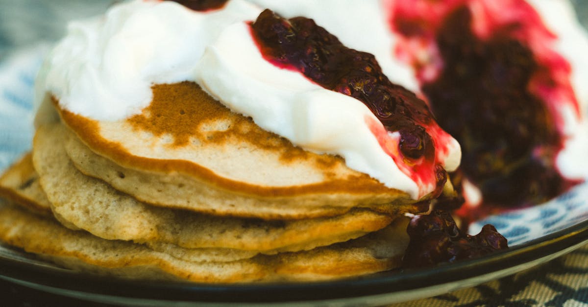 close up of pancakes topped with cream and berry sauce appetizing breakfast treat