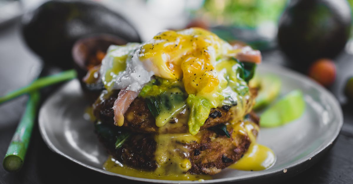 close up of poached egg with avocado on toast topped with sauce on a blurred background