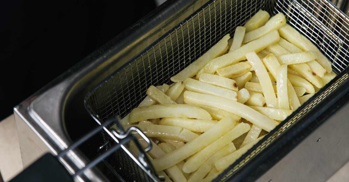 close up of raw french fries in a deep fryer basket ready for cooking