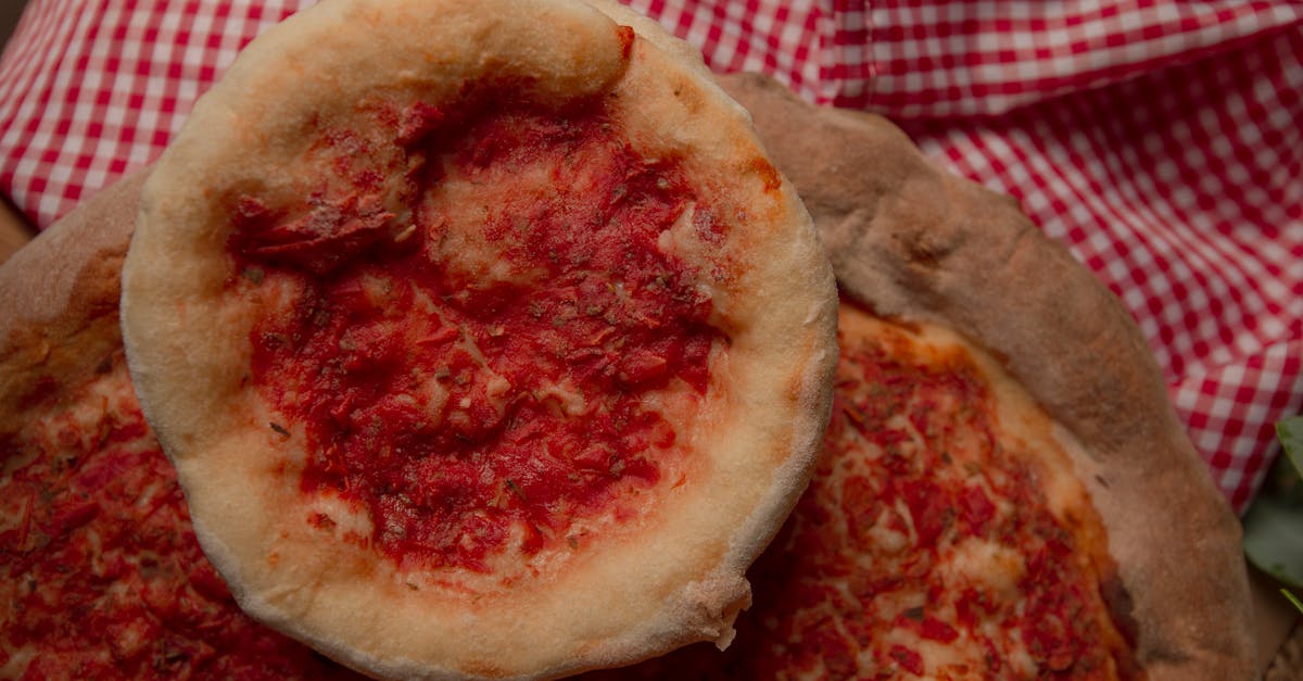 close up of rustic homemade pizzas with fresh tomato sauce on a checkered tablecloth 2