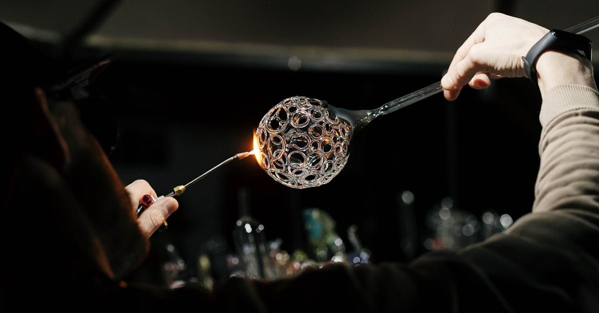 close up of skilled glassblower crafting detailed glass piece using torch in workshop