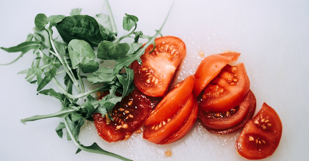 close up of sliced tomatoes and fresh greens arranged on a cutting board perfect for healthy eating