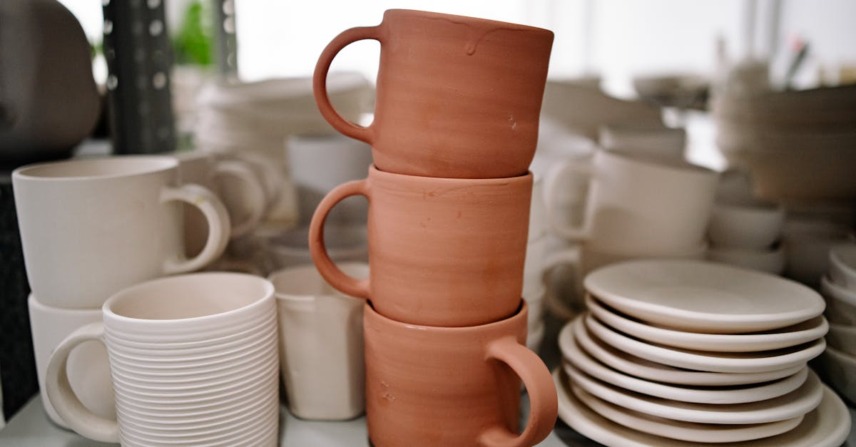 close up of stacked handmade ceramic mugs and plates showcasing pottery craft in a studio setting