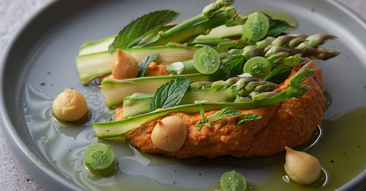 close up of vegan asparagus dish with hummus chickpeas and mint on a plate