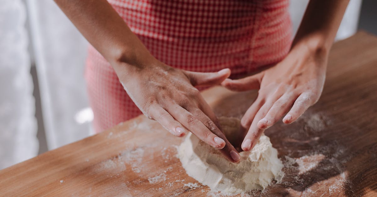 close up of woman shaping fresh pasta dough on a wooden surface