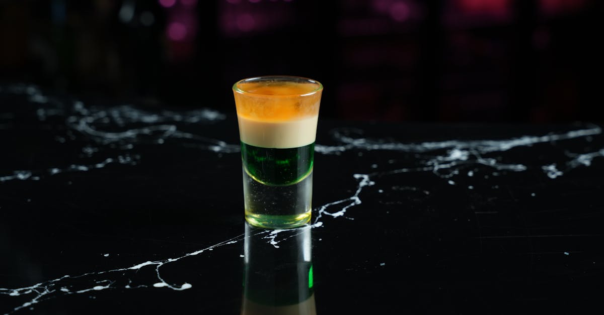 close up shot of a vibrant layered cocktail on a sleek black marble bar surface