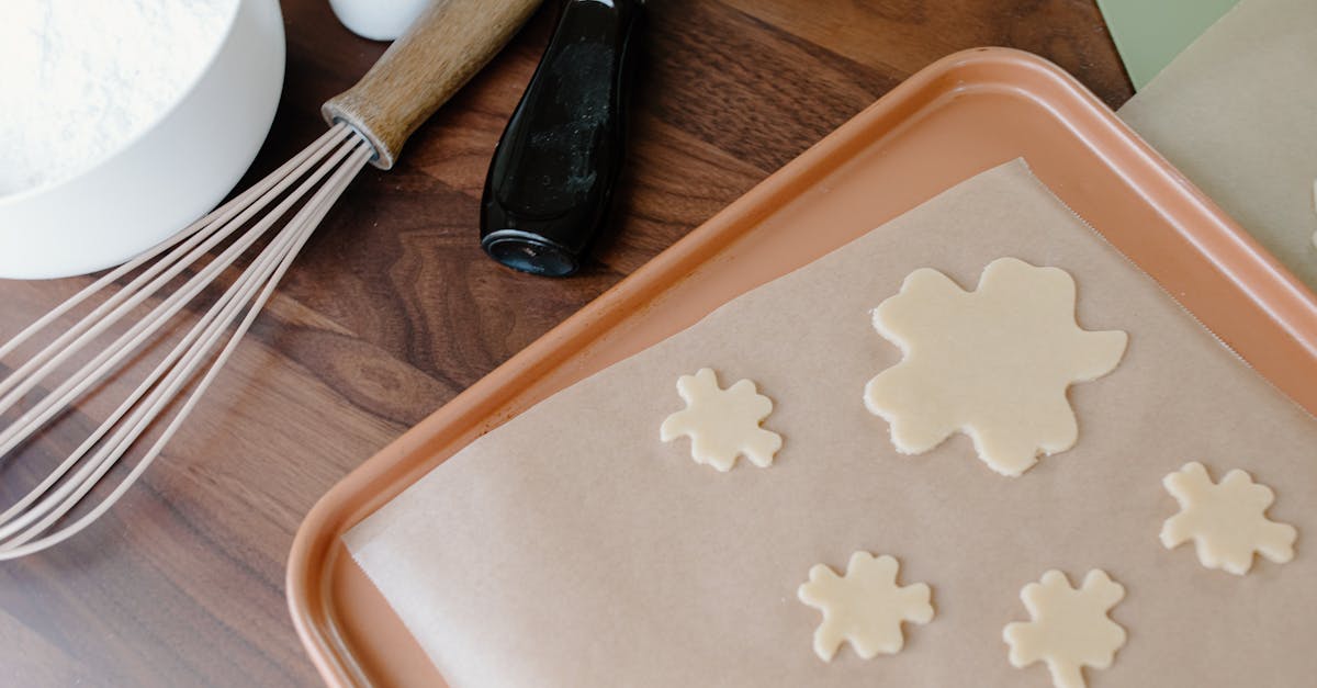 clover shaped cookie dough on parchment paper with baking utensils on wooden surface