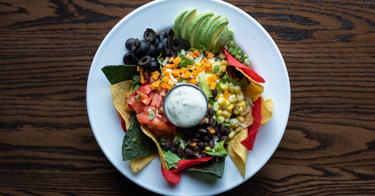 colorful plate of nachos with fresh avocado olives tomatoes and cheese for a tasty mexican meal