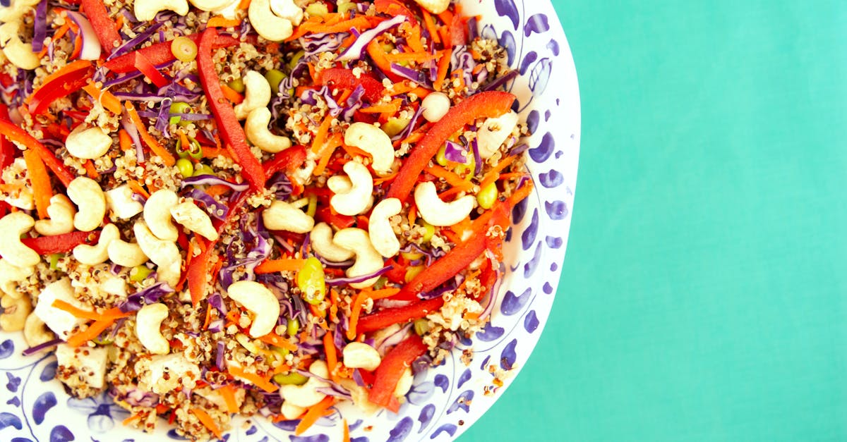 colorful quinoa salad with cashews peppers and cabbage in a decorative bowl on a turquoise backgro