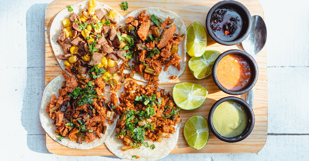 colorful vegan tacos with lime slices and dipping sauces on a wooden tray shot in bright light