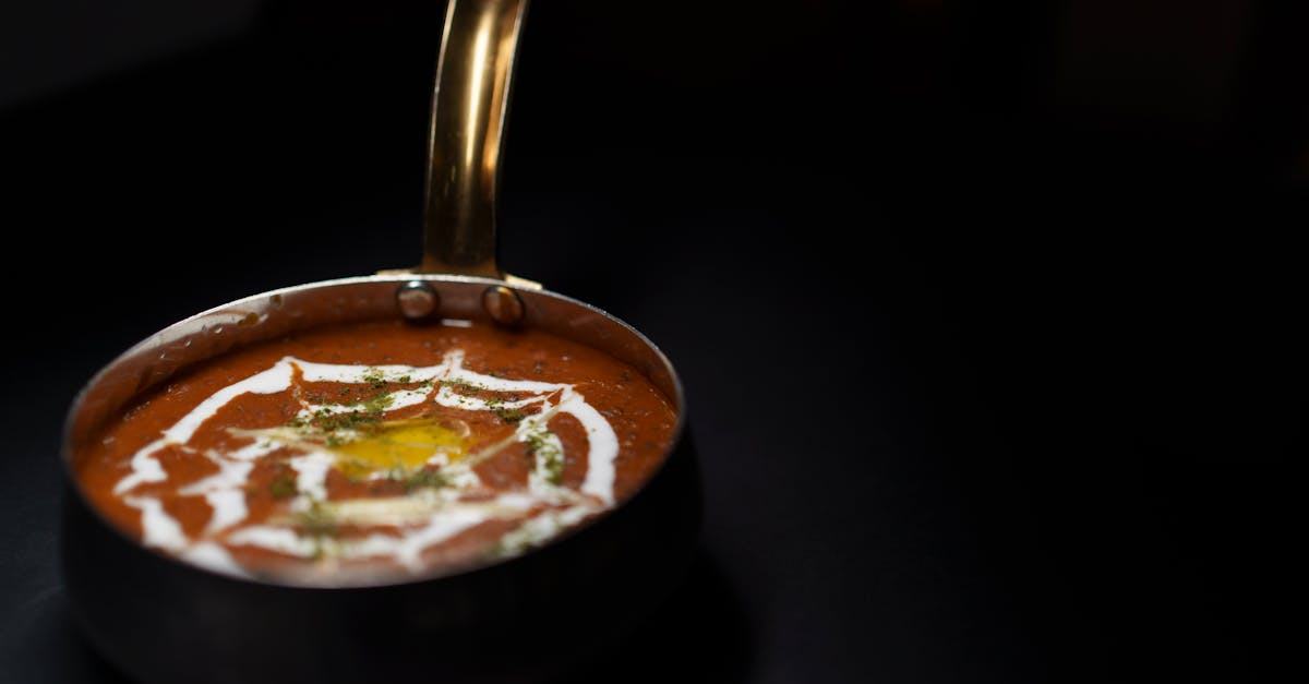 creamy dal makhani garnished with herbs and yogurt served in a brass pan on a dark background 2