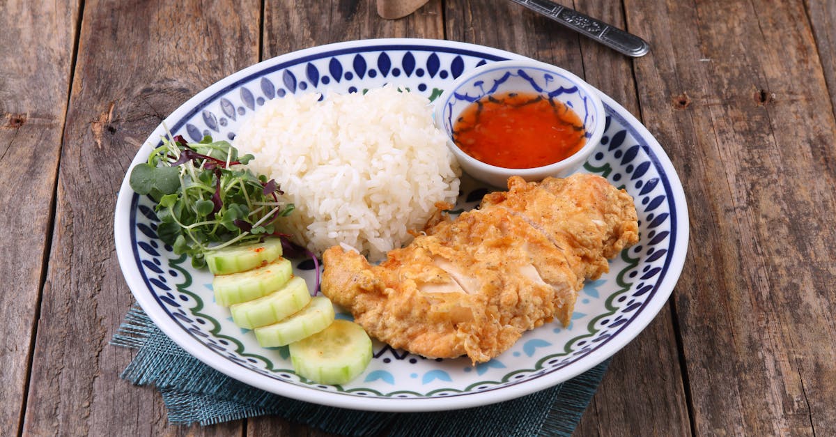crispy chicken served with rice cucumber salad and dipping sauce on a rustic wooden table
