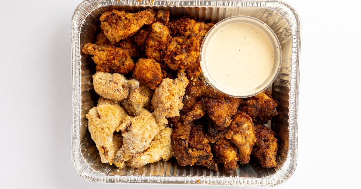 delicious assorted fried chicken nuggets with dipping sauce in a foil container