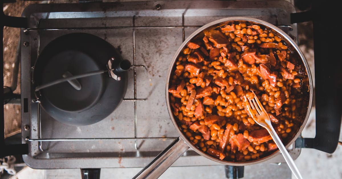 delicious baked beans and sausage simmering on a stove in a stainless steel pan