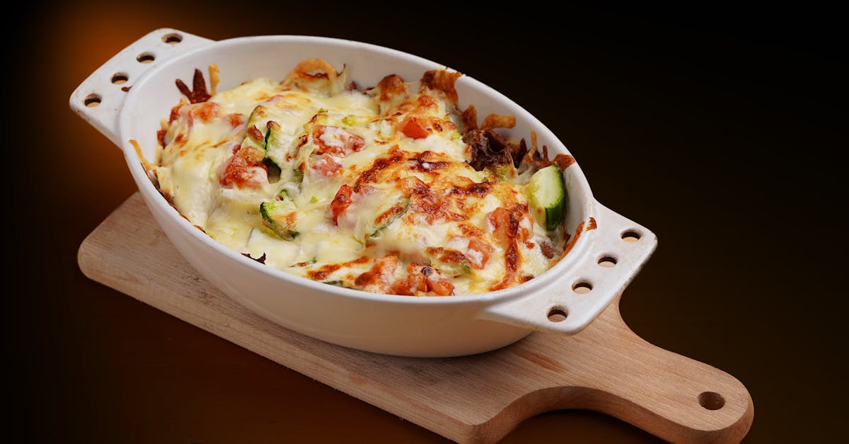 delicious baked vegetable casserole topped with cheese in a white dish on a wooden board