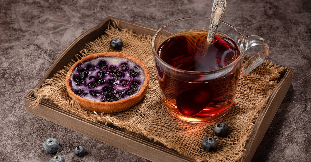 delicious blueberry tart beside glass cup of tea on a rustic wooden tray perfect for breakfast or d
