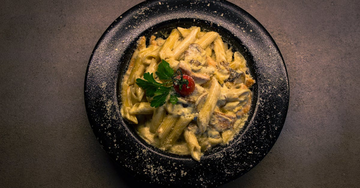 delicious creamy mushroom pasta in a dark bowl garnished with parsley and cherry tomato