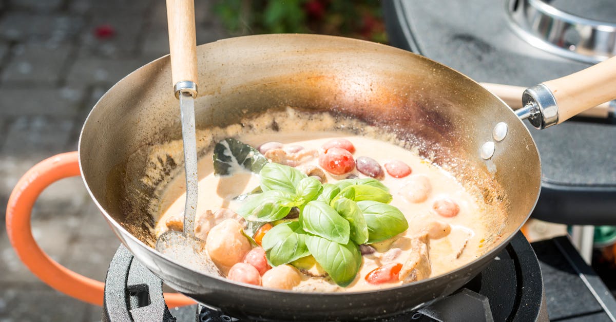 delicious creamy tomato and basil sauce being prepared in a pan on an outdoor gas stove