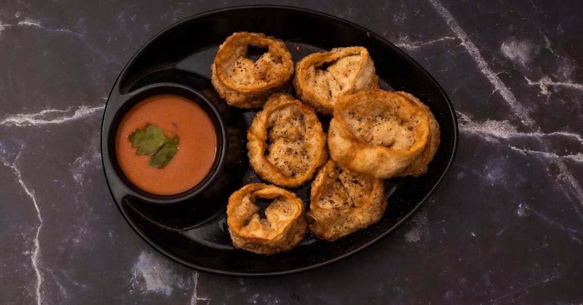 delicious crispy cheese corn momos served with a spicy dipping sauce on a black plate 1