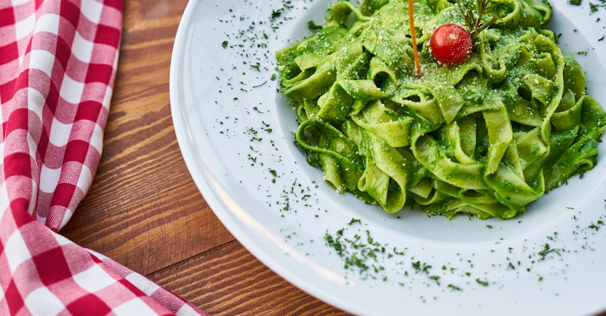 delicious fettuccine pasta tossed in vibrant green pesto garnished with a cherry tomato perfect fo