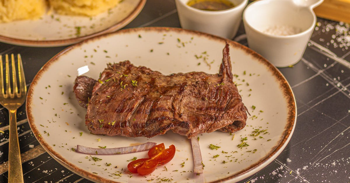 delicious grilled steak on a white plate garnished with herbs and served with mash and sauces
